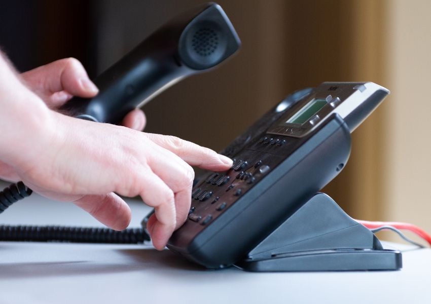 person putting dialling numbers on a landline phone